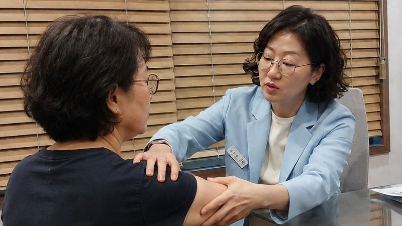 오십견 상담, 원장이 환자의 팔을 들어 어깨 가동범위를 확인하는 장면
