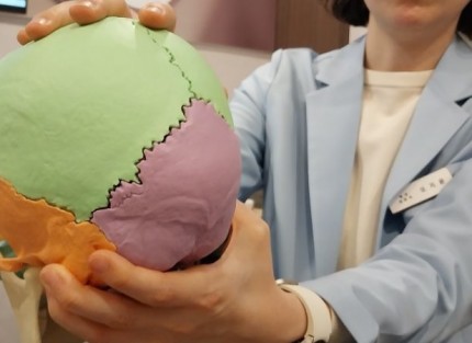 진료실에서 두통 환자와 원장이 마주 앉아 상담하는 모습